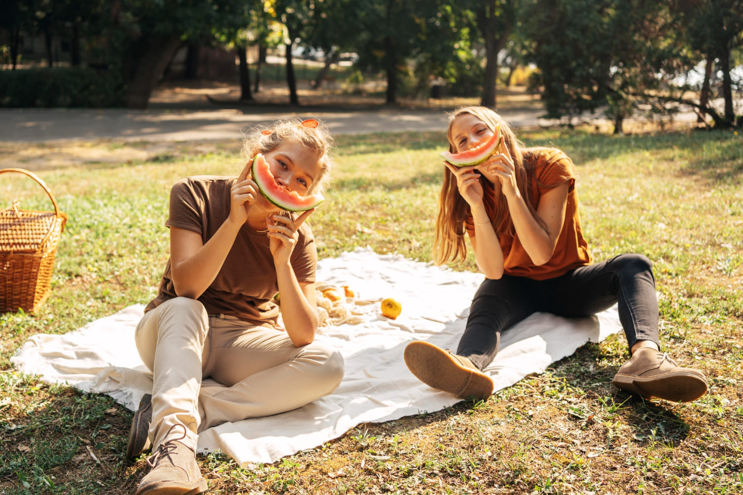 Organiser un pique-nique entre amis parfait Groupe d’amis installés sur une nappe avec des paniers et des pastèques pour un pique-nique